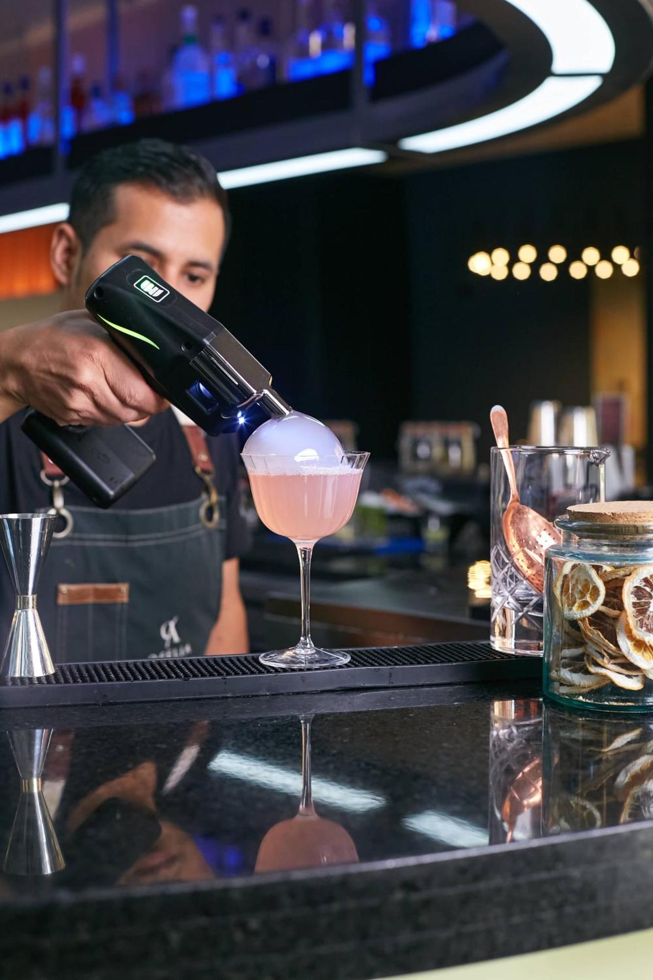 Pullman Santiago Vitacura Экстерьер фото A bartender using a blowtorch to cook a cocktail